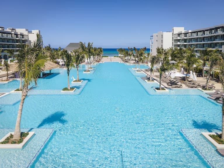 The sweeping turquoise pool at Ocean Eden Bay Resort in Jamaica, lined with palms and resort buildings
